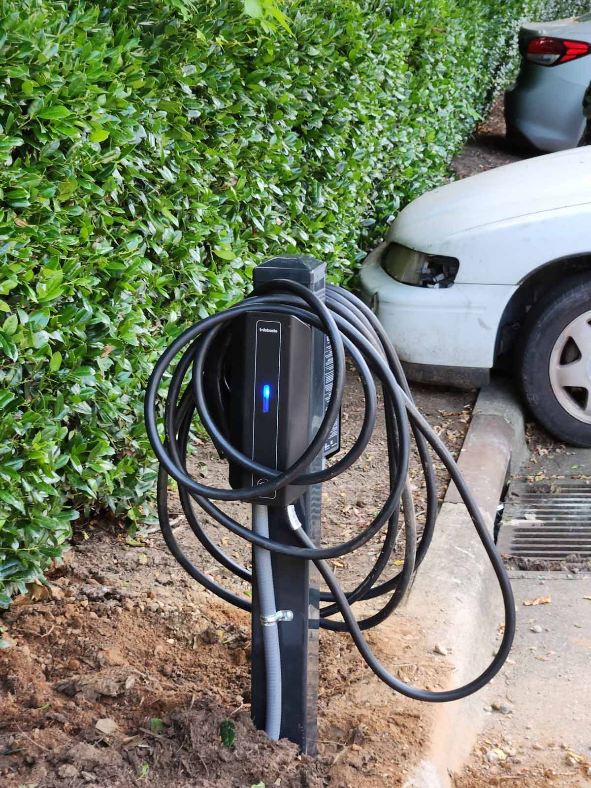 A car is being charged at a charging station in a parking lot.