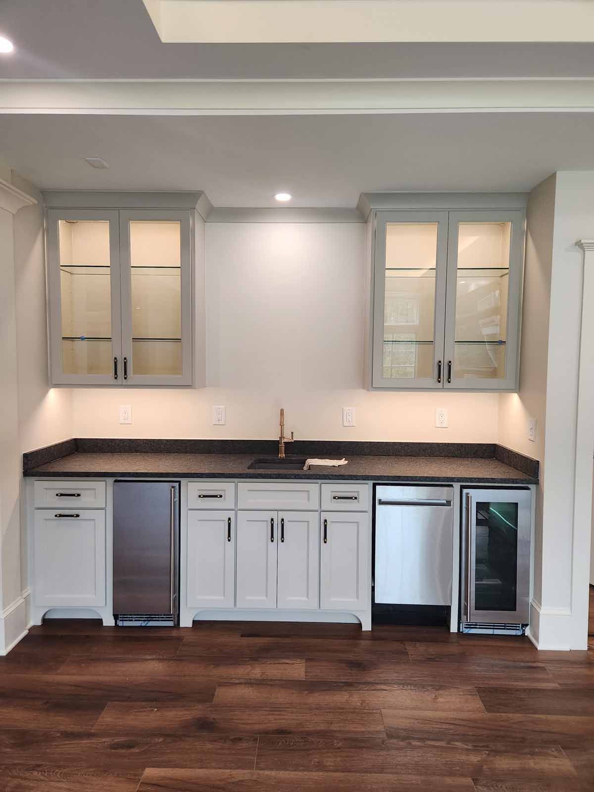 A kitchen with white cabinets , stainless steel appliances , a sink , and a refrigerator.