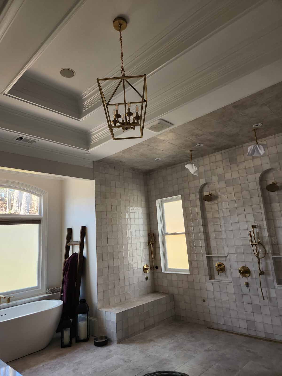 A bathroom with a bathtub , showers , and a chandelier hanging from the ceiling.