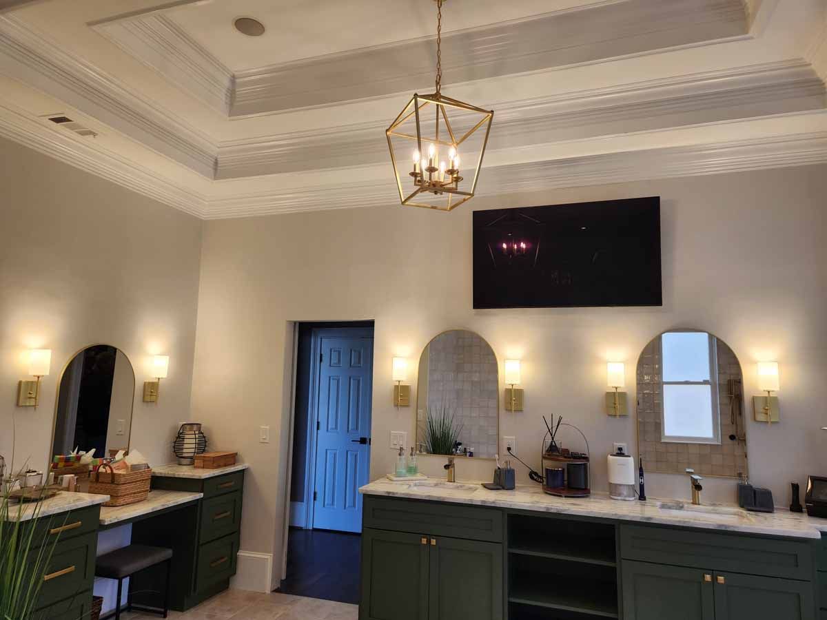 A bathroom with two sinks , two mirrors and a chandelier.