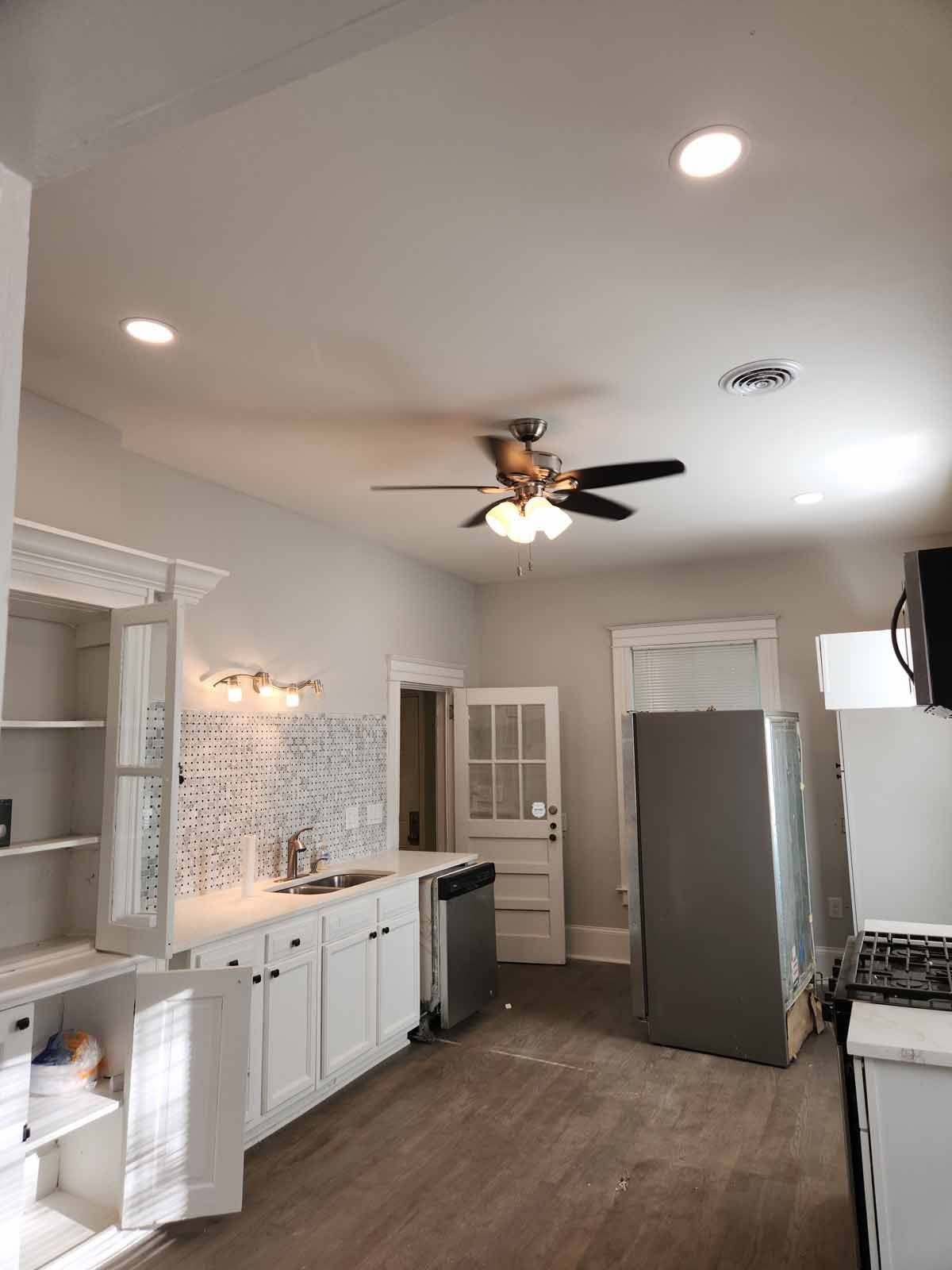 A kitchen with white cabinets and a ceiling fan.