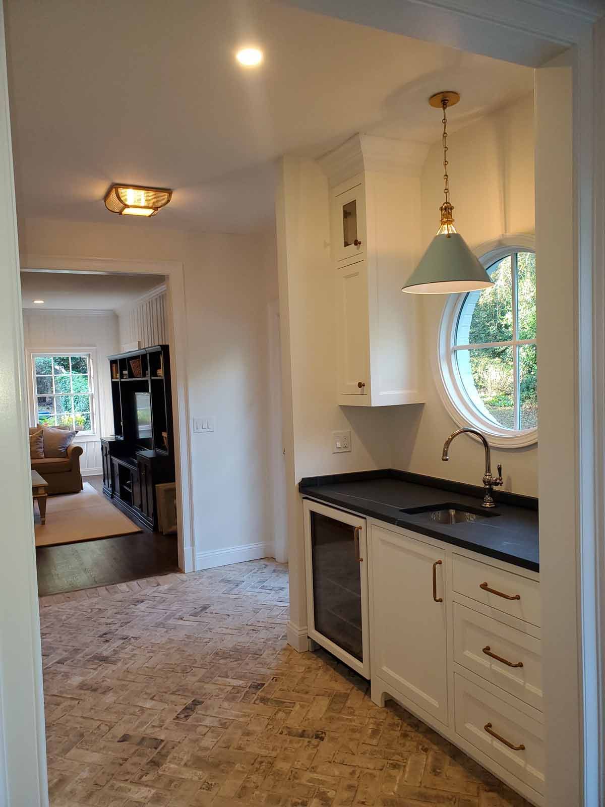 A kitchen with a sink , refrigerator , and a round window.