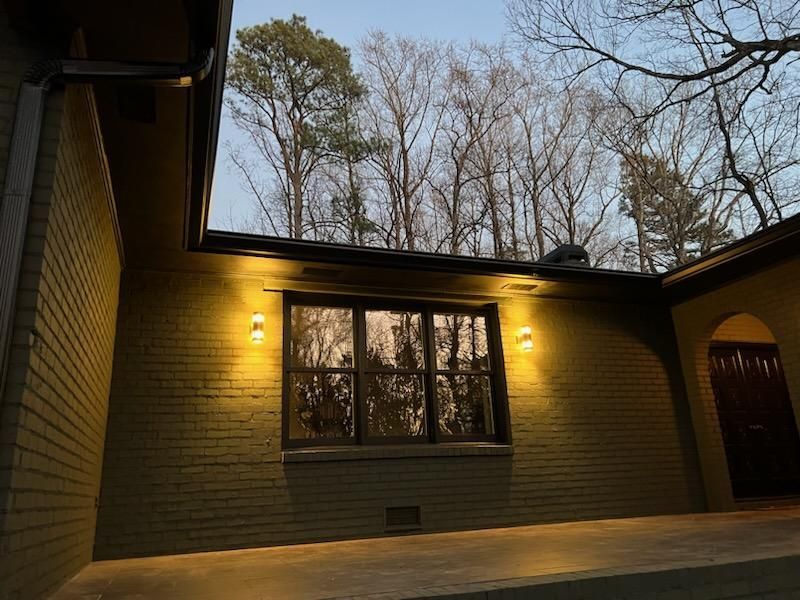 A brick house with a large window and trees in the background