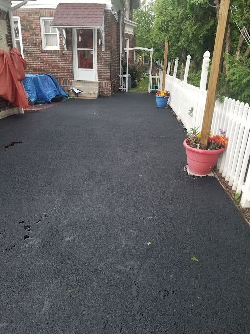 A Brick House with a Black Driveway and a White Picket Fence — Kutztown, PA — B Young Paving