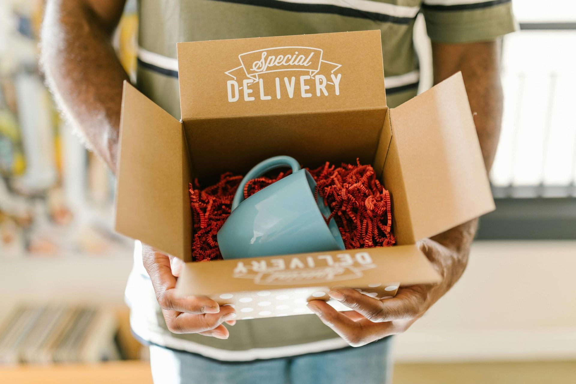 Someone holding a box that says delivery with a blue mug