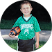 A young boy in a green jersey is holding a soccer ball.