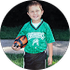 A young boy in a green jersey is holding a soccer ball.