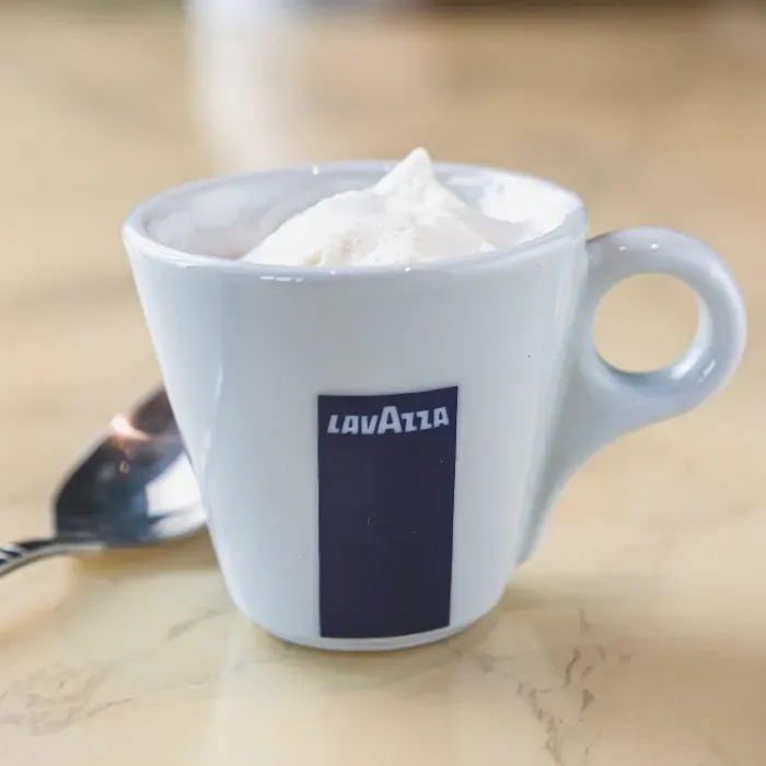 A cup of lavazza coffee with whipped cream in it