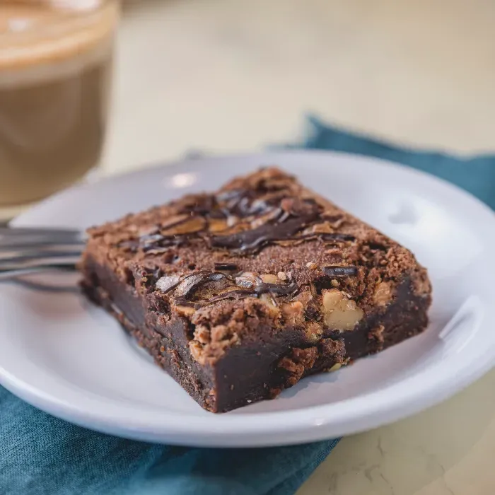 A piece of brownie on a white plate with a fork