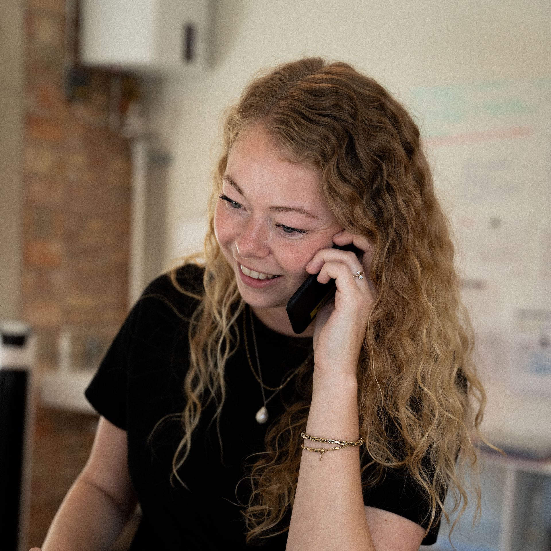 Een vrouw lacht terwijl ze op een mobiele telefoon praat