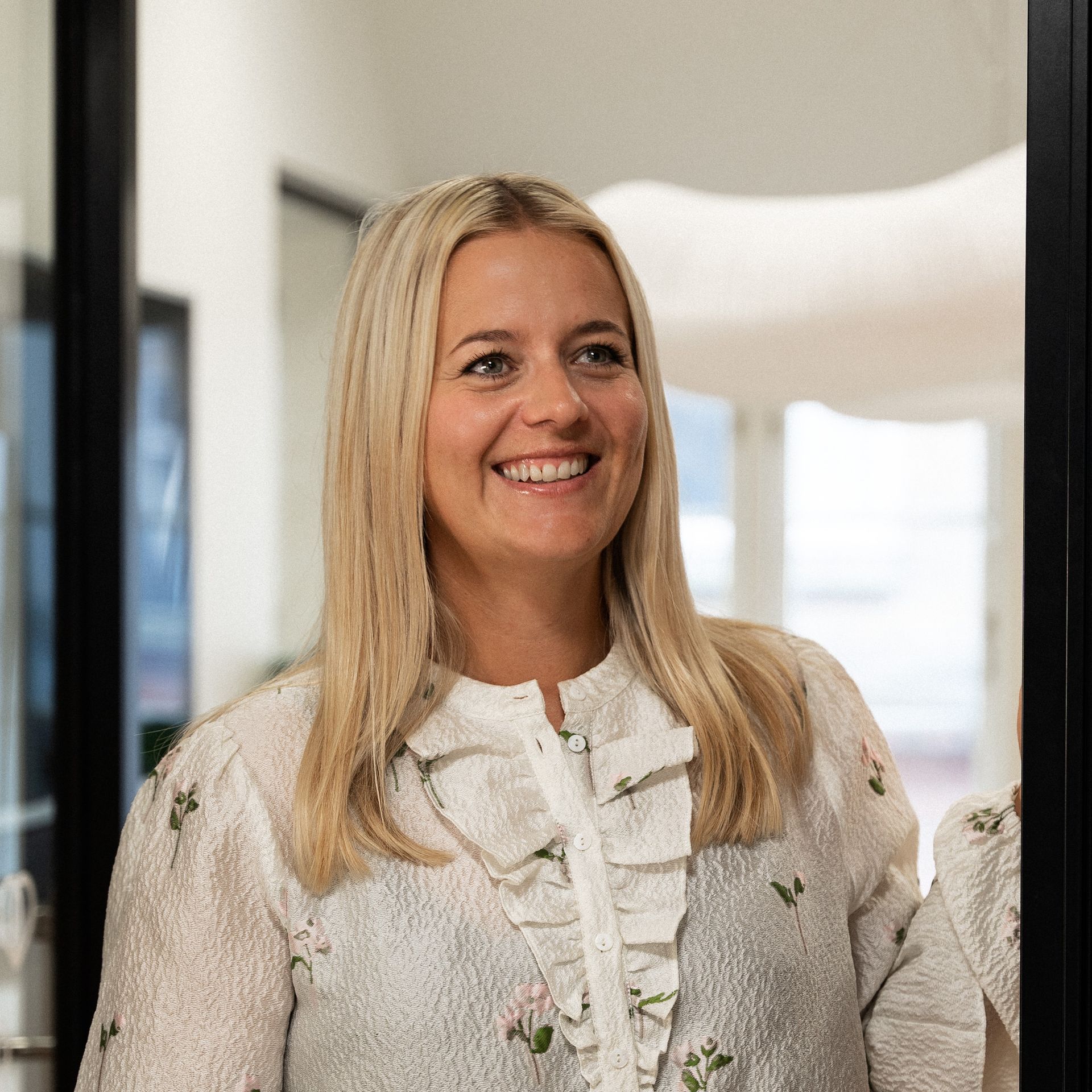 Een vrouw met blond haar lacht voor de spiegel