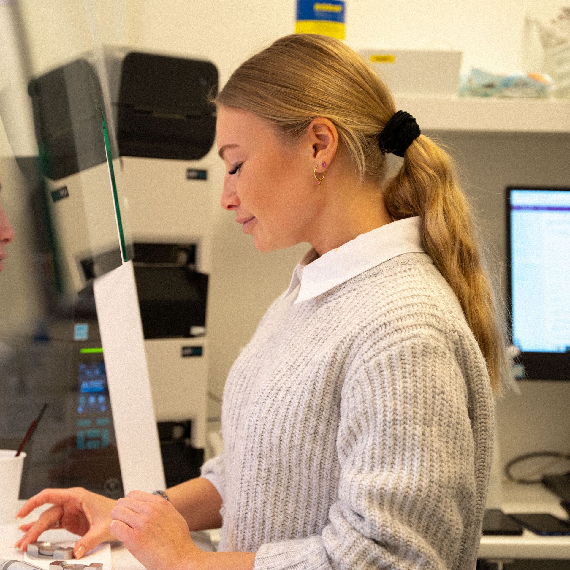 Een vrouw in een grijze trui werkt op een computer