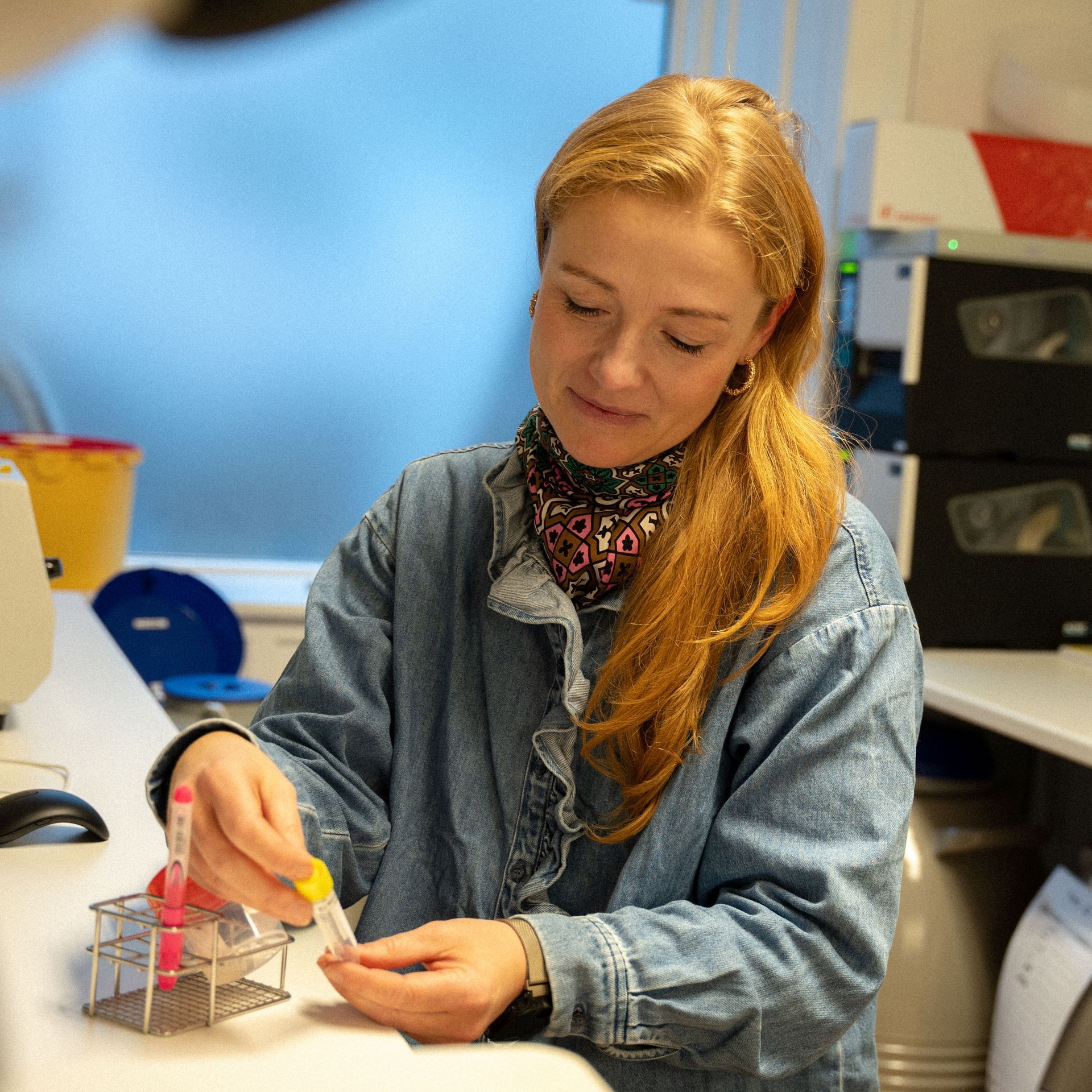 Een vrouw in een spijkerjasje werkt in een laboratorium