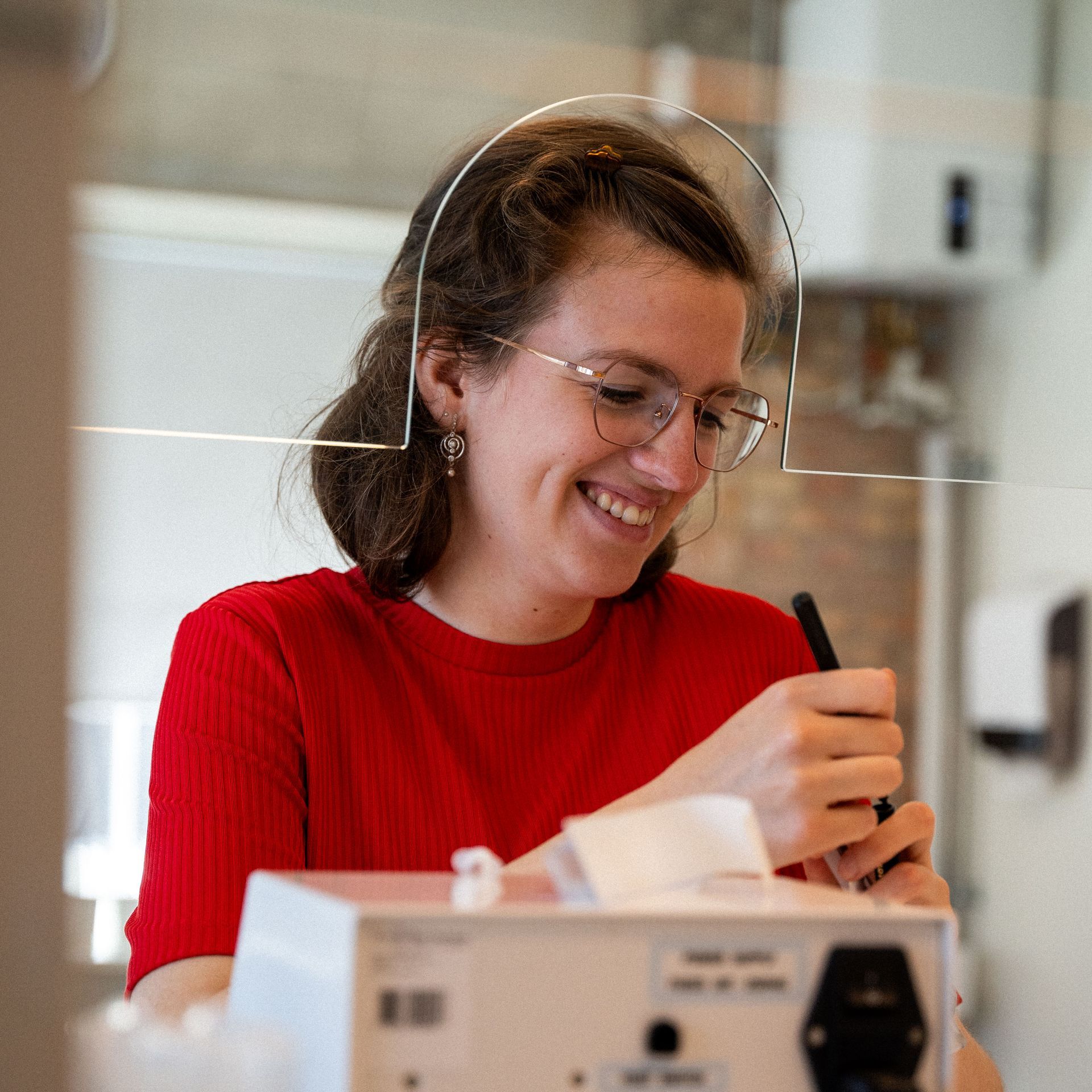 Een vrouw met een bril en een rood shirt lacht