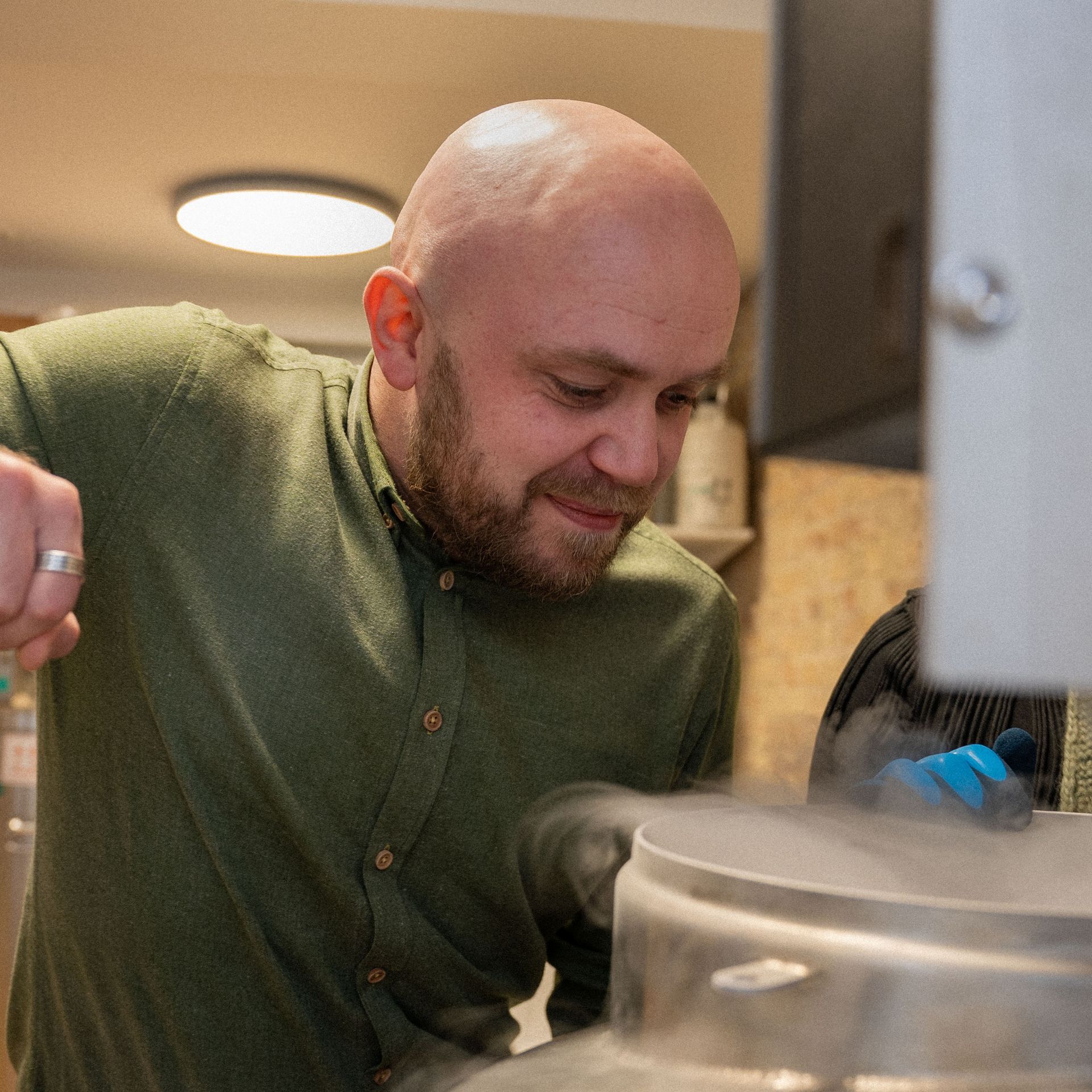 Een man in een groen shirt werkt aan een machine