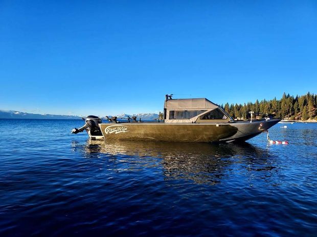 Four people fishing from a boat on a calm sea, using fishing rods. 