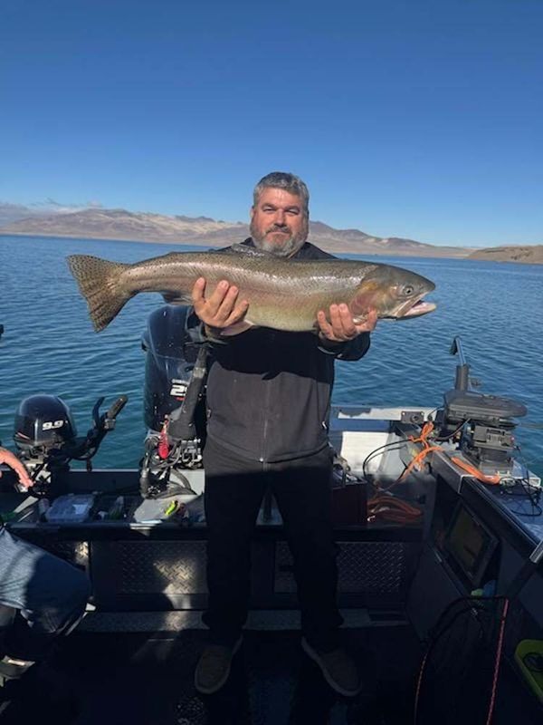 Man on a boat holds up a large fish.