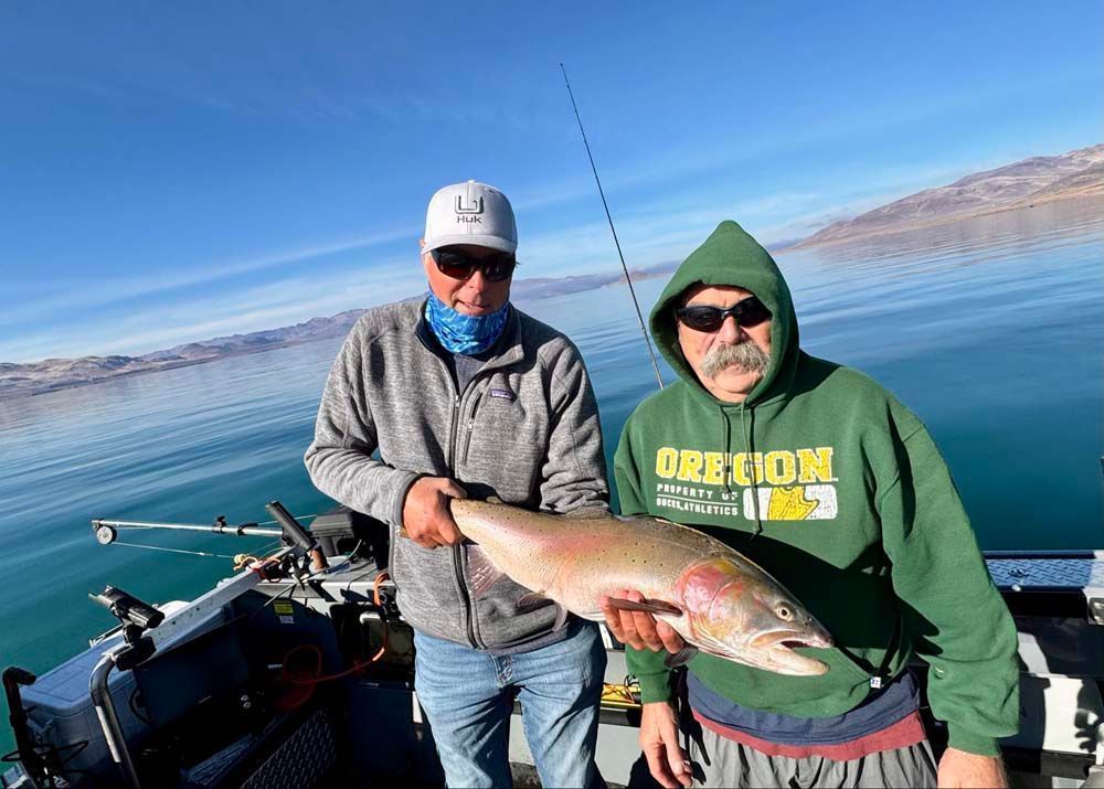 Two men on a boat hold up a large fish, on a sunny day.