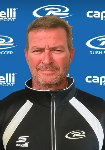 Man in black and white athletic jacket; blue background with sports logos.