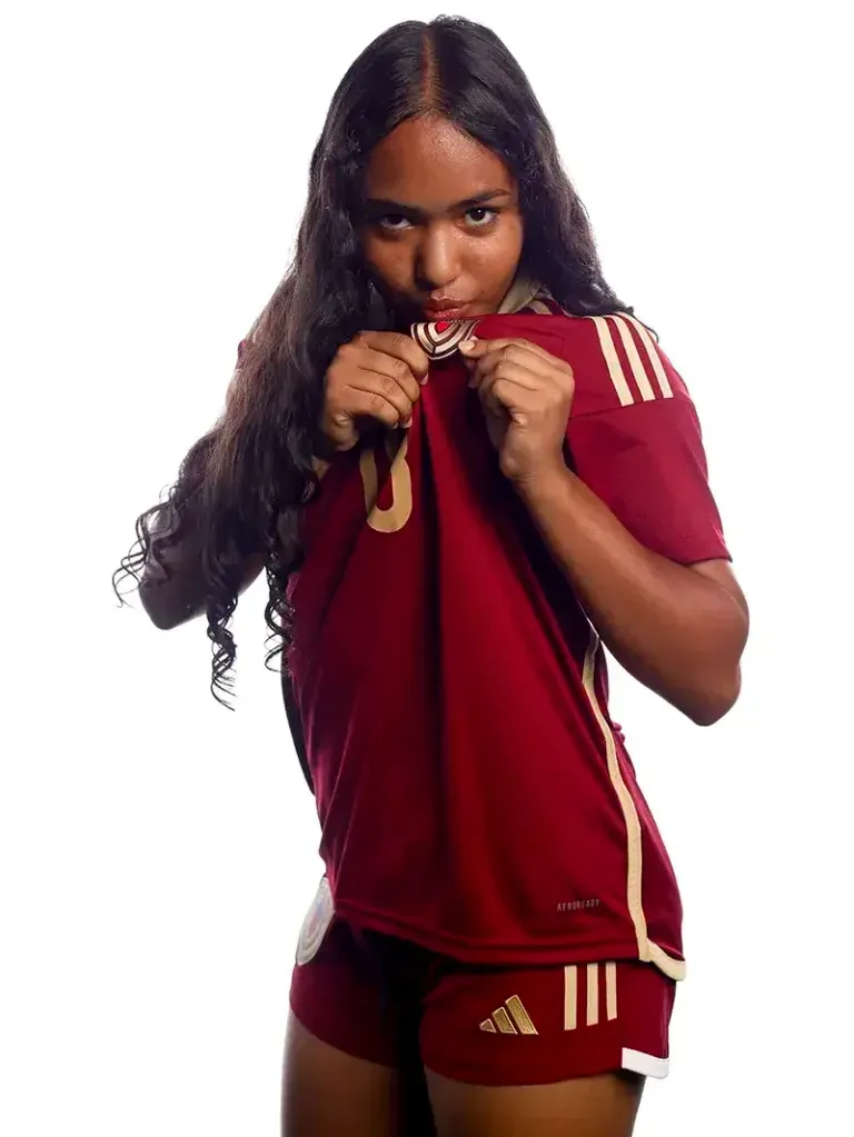 Soccer player in burgundy uniform holding jersey.