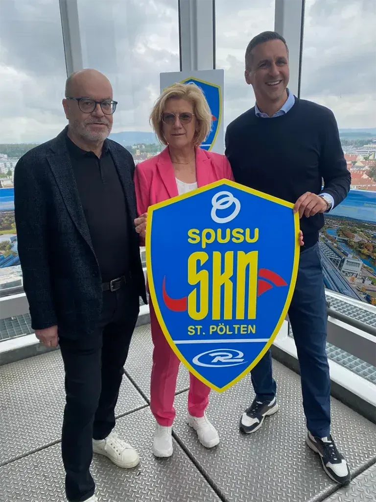 Three people holding a blue and yellow shield with 