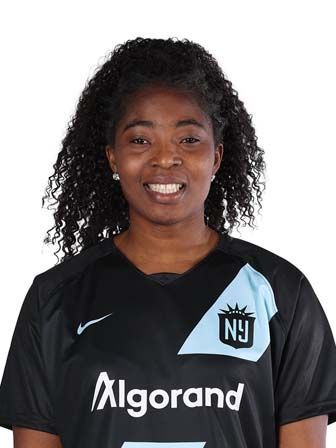 Jennifer Cudjoe in soccer jersey smiling at the camera, team logo visible.