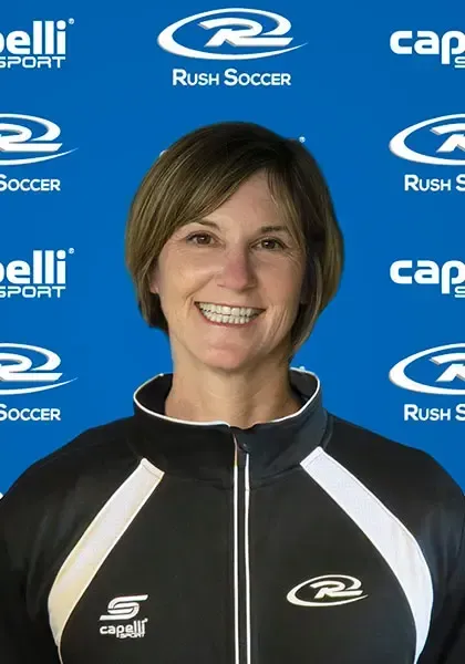Woman with short brown hair, smiling, wearing a black and white athletic jacket