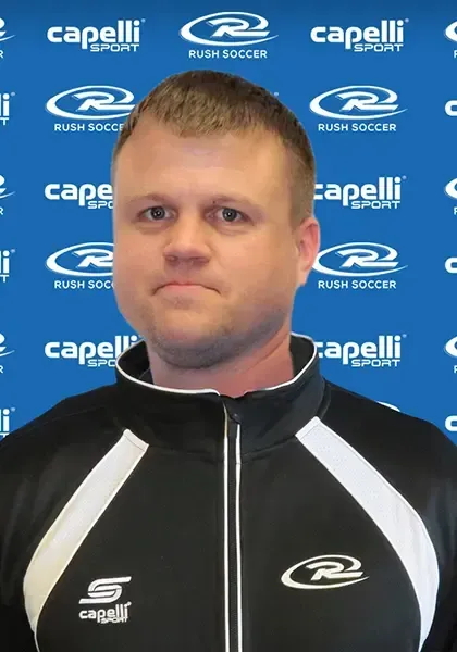 Man wearing a black and white track jacket, standing in front of a blue background with logos.