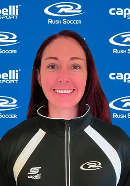 Woman in black and white athletic wear smiling, with soccer logos on the blue background.
