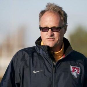 Man in dark sunglasses and USA jacket, looking forward on a field.