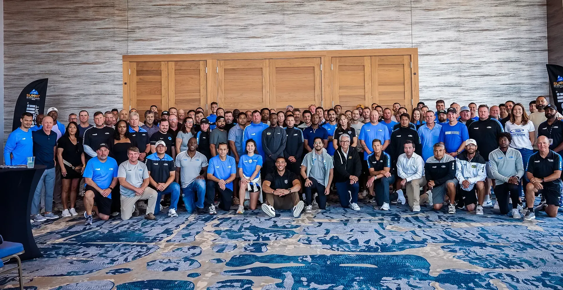 Woman gesturing with hands, speaking. Wearing a gray hoodie, indoors near a table.