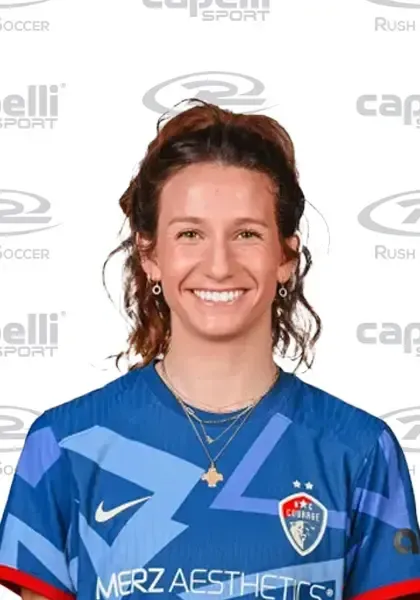 Ryan Williams with brown hair smiles, wearing a Rush soccer jersey with sponsors' logos.