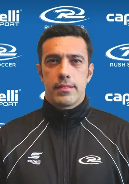 Man in black jacket with logo on a blue background.