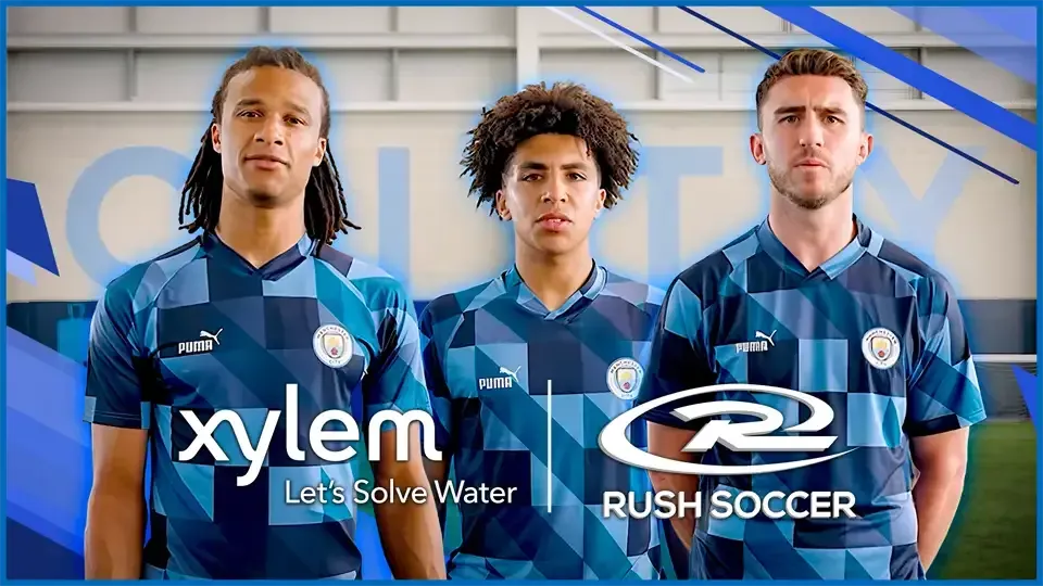 Three soccer players in blue jerseys with sponsor logos and the word 