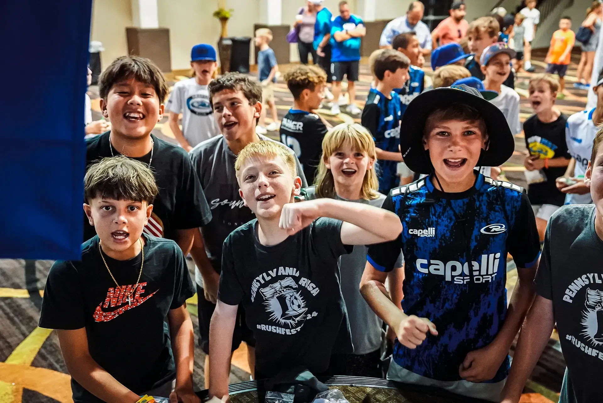 Group of excited kids posing, some wearing sports jerseys, indoors.