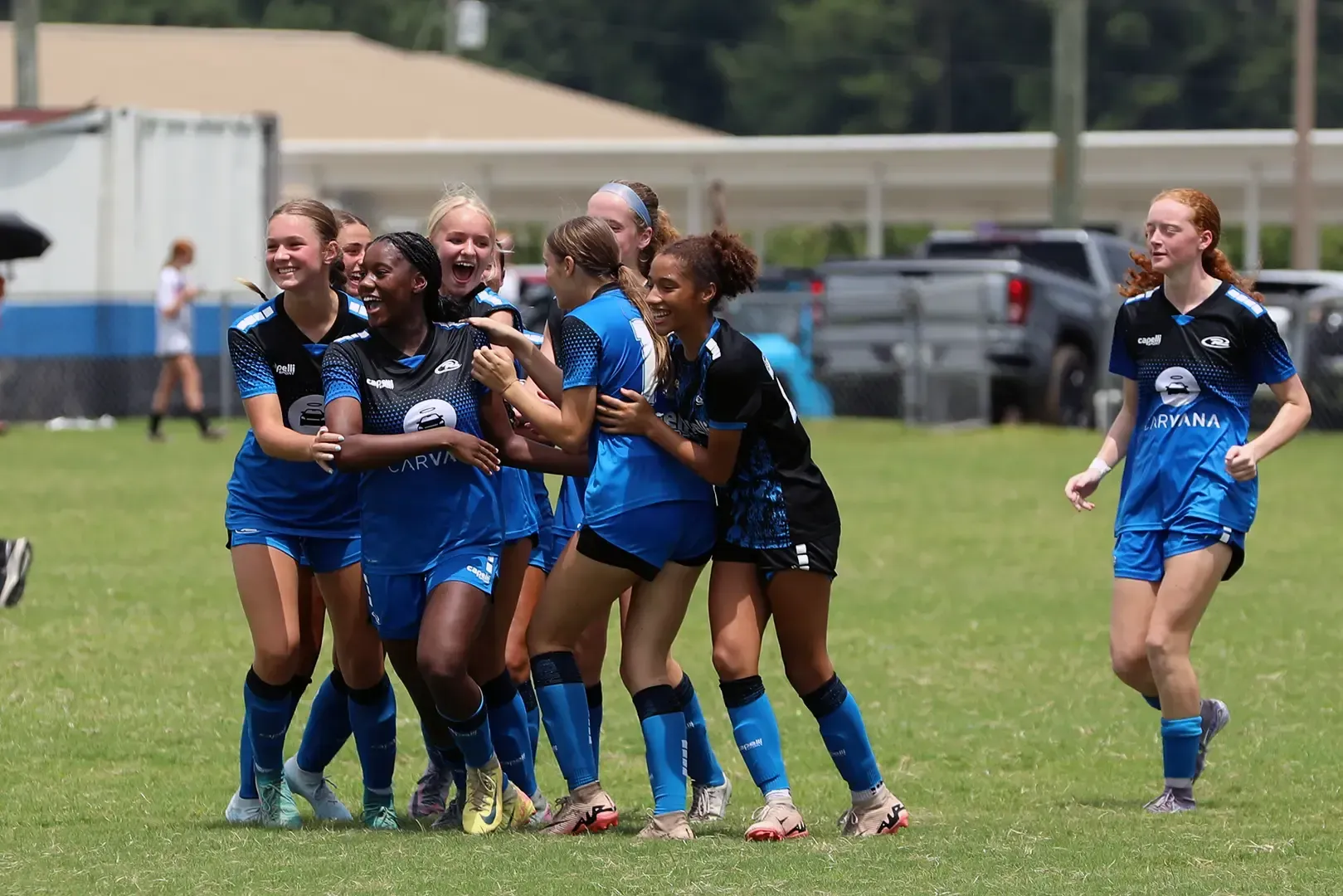 Soccer team in blue and black jerseys celebrating on a grassy field.