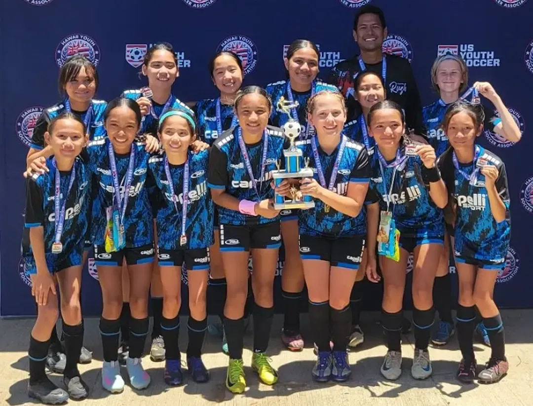 Youth soccer team in blue and black uniforms with a trophy.