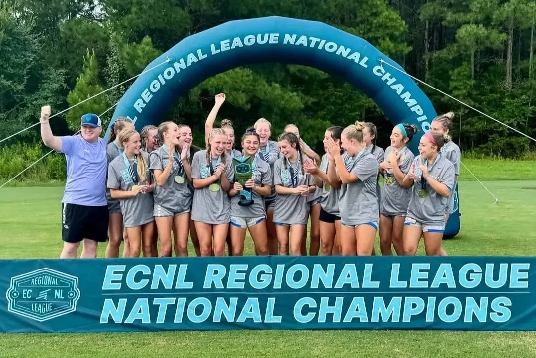 Soccer team celebrating Regional League National Championship victory. Team holding trophy under inflatable arch.