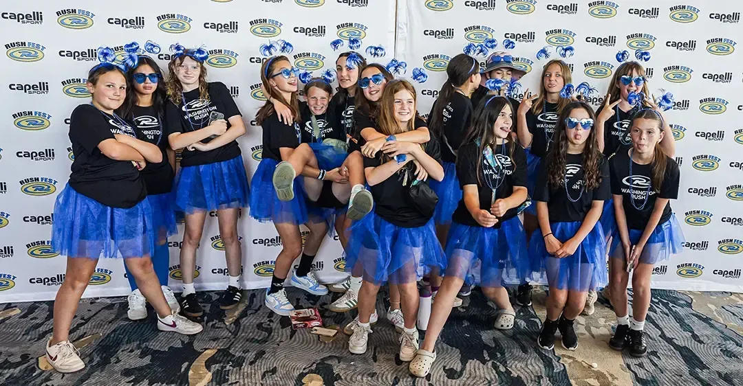 Group of girls in blue tutus and face paint pose in front of a backdrop.