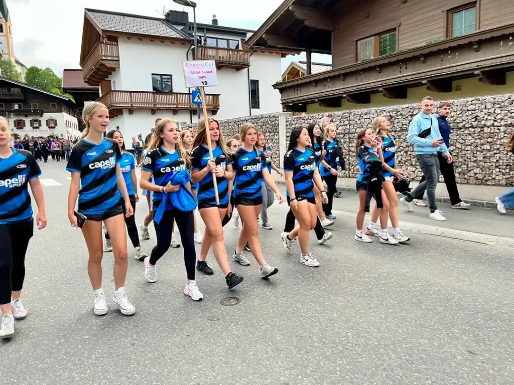 A group of young women in blue and black uniforms marching in a street parade.