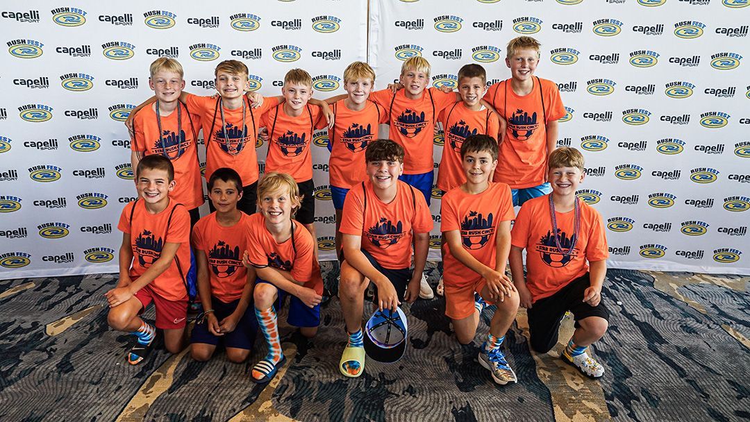 Youth sports team wearing orange shirts poses for a group photo.