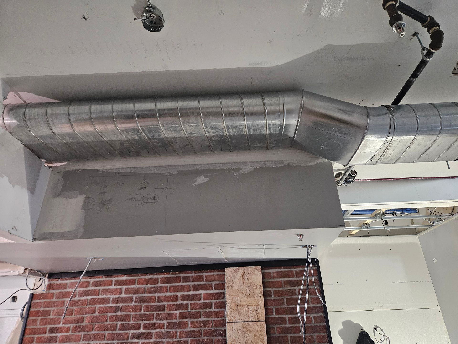 A metal pipe is hanging from the ceiling in a room with a brick wall.