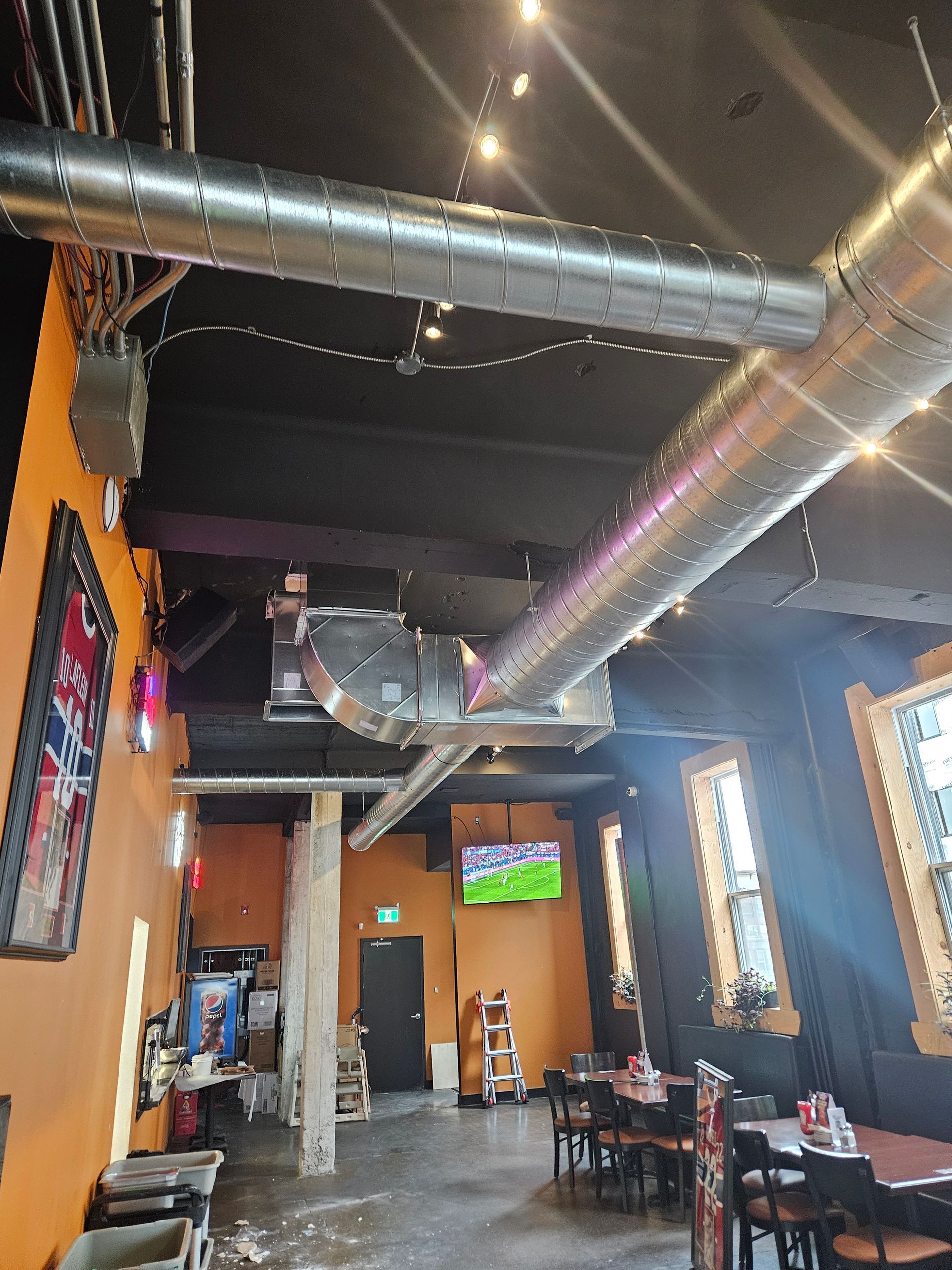 Un restaurant avec des tables et des chaises et une télévision au mur