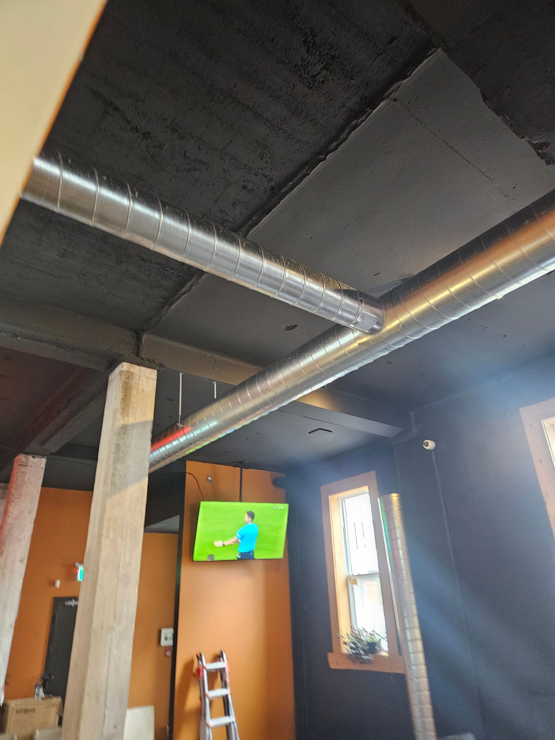 Une pièce avec une échelle et une télévision au mur