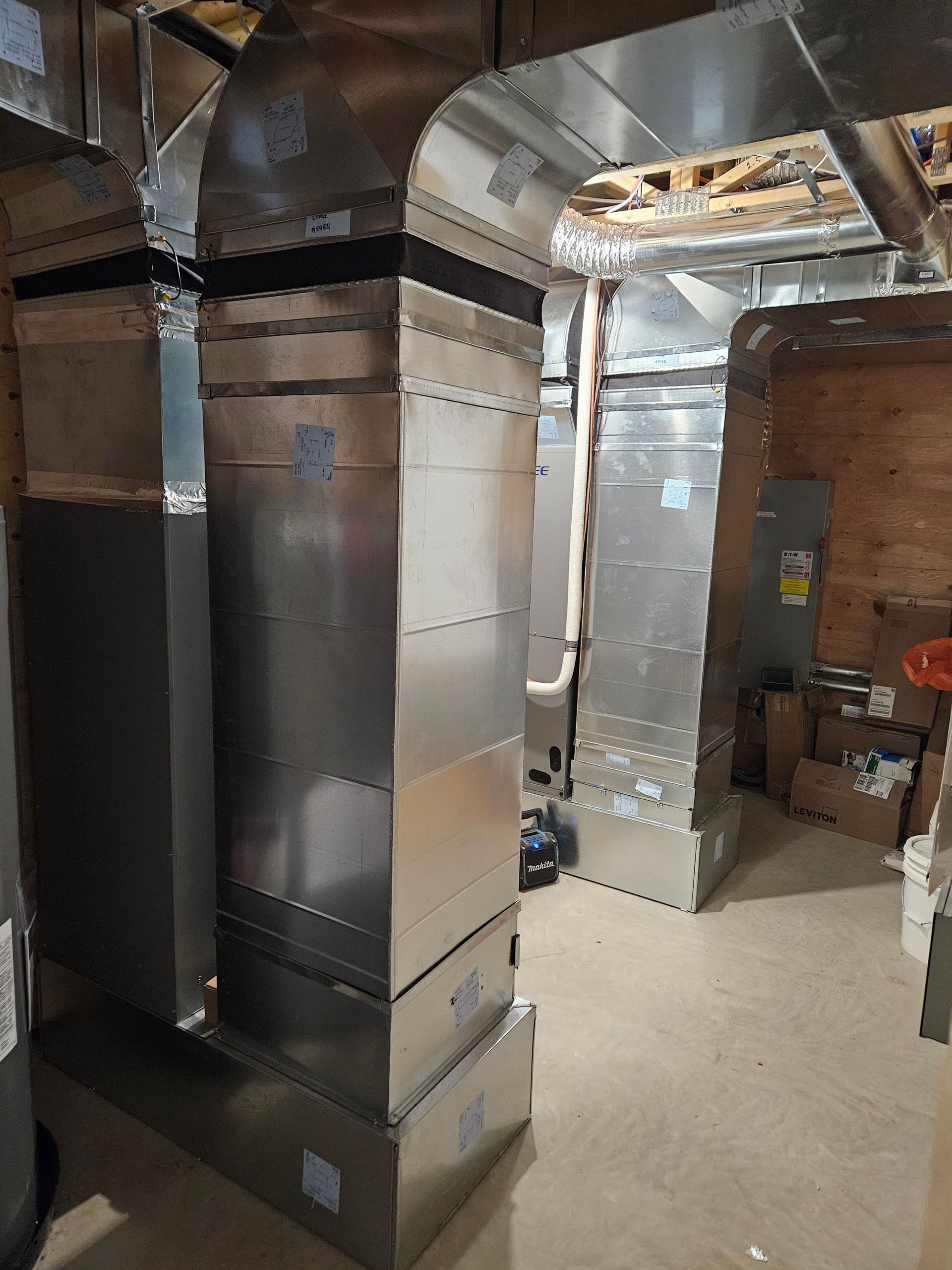 Une pièce avec beaucoup de tuyaux en acier inoxydable sortant du plafond.