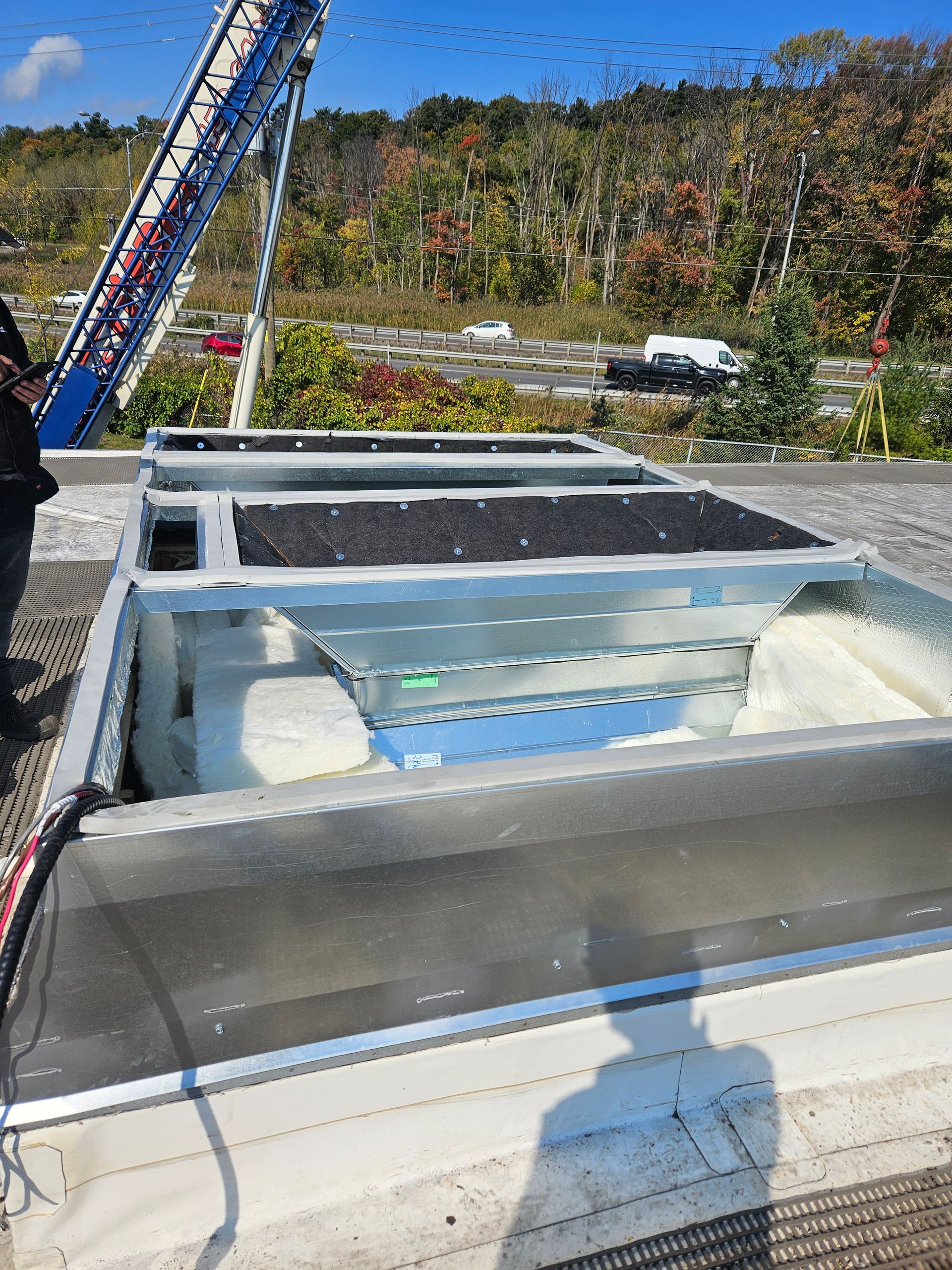 Un homme se tient debout sur un toit avec une grue en arrière-plan.