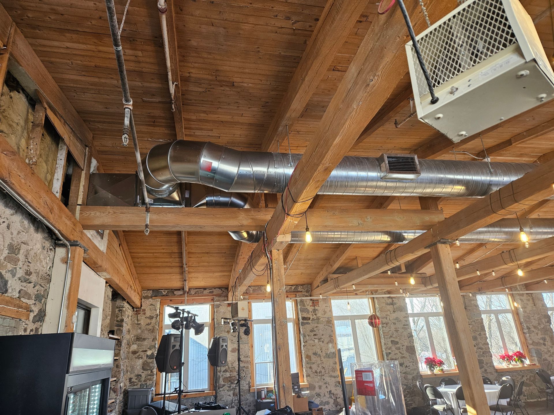 Une grande pièce avec un plafond en bois et beaucoup de tuyaux qui y pendent.