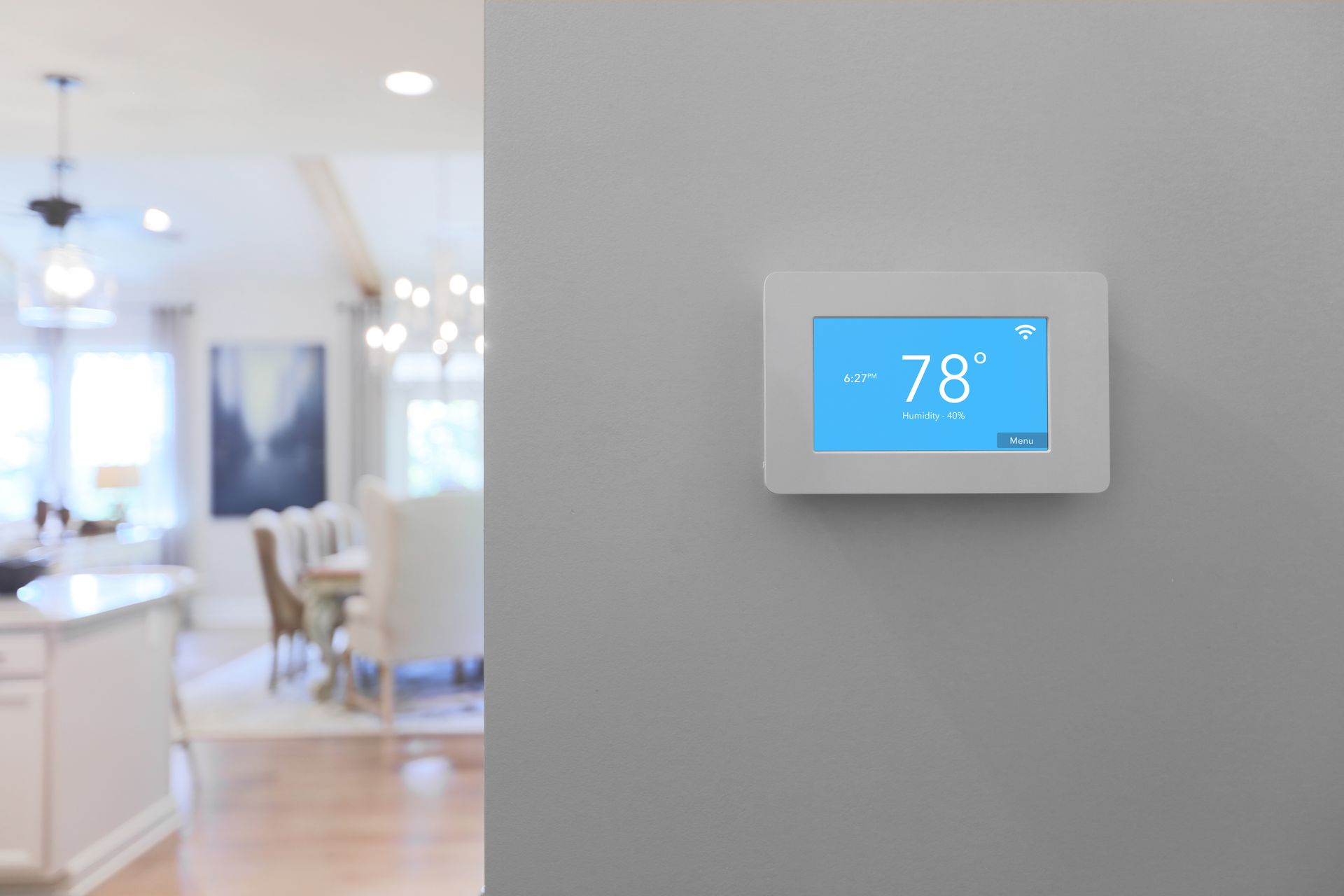 A white thermostat is hanging on a wall in a living room.
