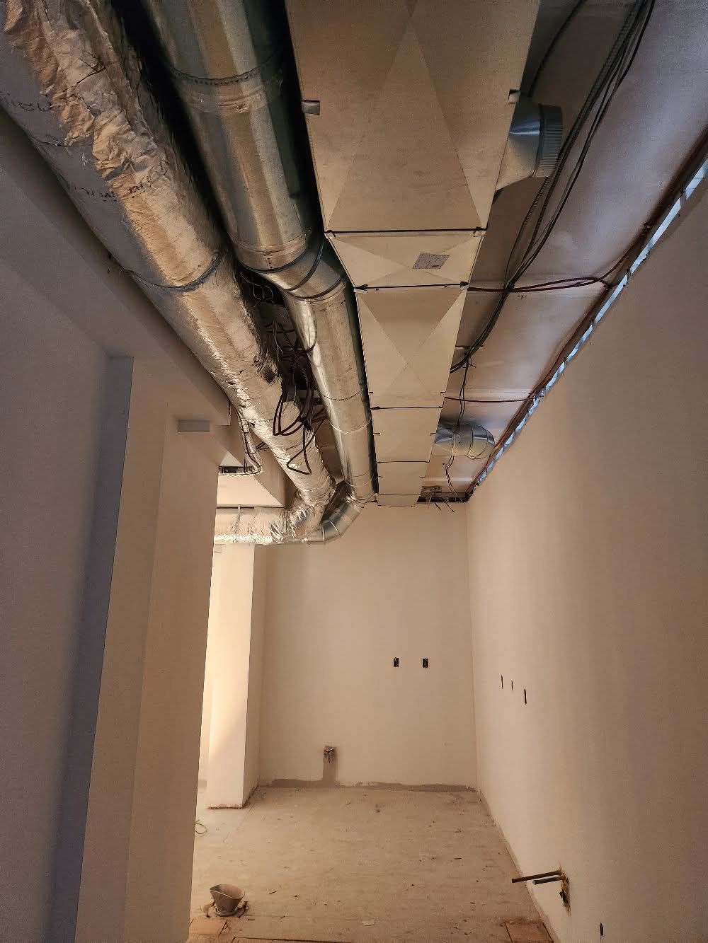 Un couloir avec beaucoup de tuyaux suspendus au plafond.