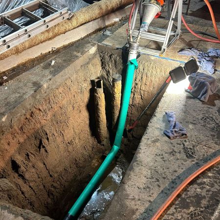 Pride Plumbing, Inc | A green pipe is being installed in a hole in the ground.